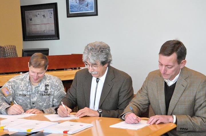 Three people signing papers to help The Tulalip Tribes establish the first Native American aquatic resource program of its kind in the nation.
